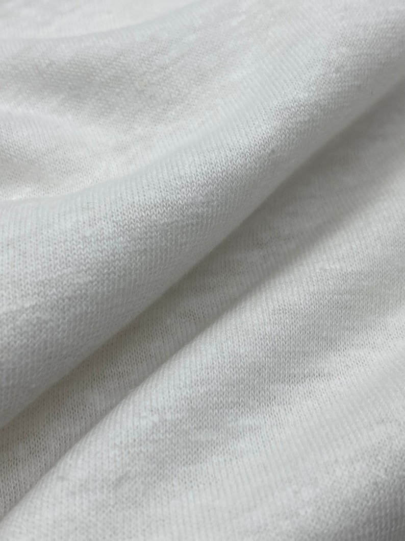 May include: Close-up of a white knitted fabric with a textured surface.