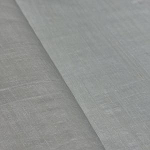 Puede incluir: Primer plano de una tela gris claro con un tejido sutil y texturizado. La tela est&aacute; doblada, creando l&iacute;neas diagonales y sombras. El material parece suave y ligero, adecuado para ropa o decoraci&oacute;n del hogar.