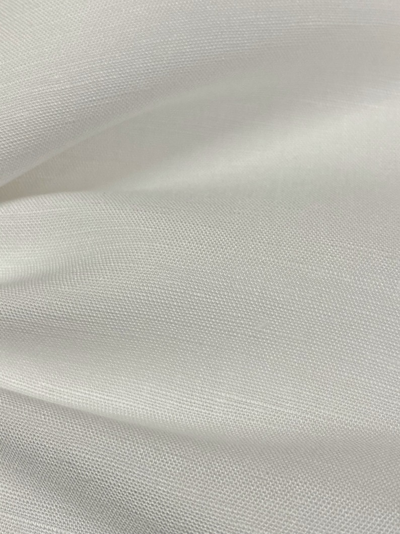 May include: White tulle fabric with a fine, even weave. The fabric is soft and delicate, with a slightly sheer appearance.