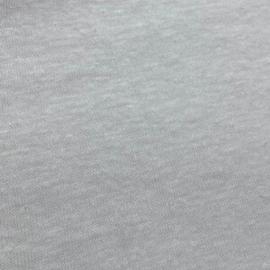May include: Close-up of a light gray fabric with a textured surface.