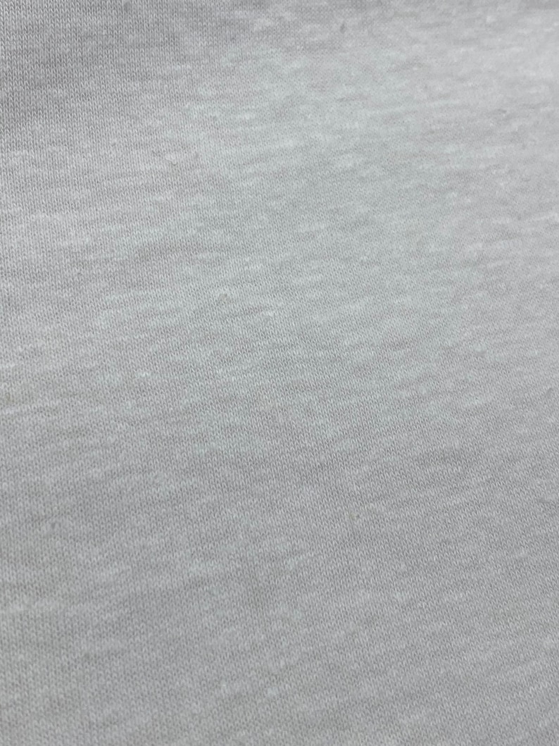 May include: Close-up of a light gray fabric with a textured surface.