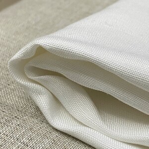 May include: White fabric with a smooth, silky texture. The fabric is folded in half and has a slight sheen.