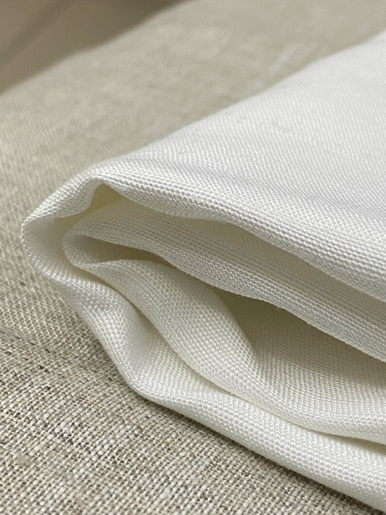 May include: White fabric with a smooth, silky texture. The fabric is folded in half and has a slight sheen.