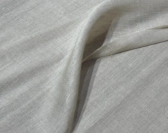 May include: A close-up of a light gray fabric with a subtle sheen. The fabric is draped, showing soft folds and textures. The material appears to be lightweight, possibly linen or a similar textile.