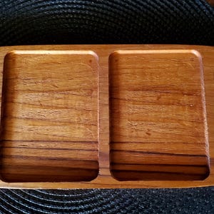 May include: A wooden serving tray with four separate compartments. The tray is oval shaped and has a natural wood finish.