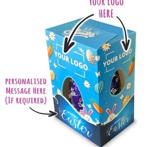 Puede incluir: Caja de cartón azul y blanca con una ventana que muestra un huevo de chocolate morado. La caja tiene un diseño de Feliz Pascua con conejos y zanahorias. La caja tiene dos áreas para agregar un logotipo.