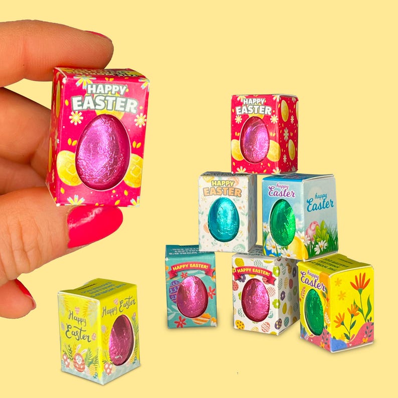 May include: Assortment of small boxes with colorful Easter egg designs. Each box contains a foil-wrapped chocolate egg. The boxes have the text "Happy Easter" on them.