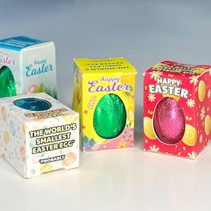 May include: Four small boxes with colorful Easter egg designs. Each box contains a small chocolate egg wrapped in foil. One box has the text "The World's Smallest Easter Egg" and "Probably" printed on it.