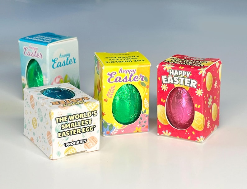 May include: Four small boxes with colorful Easter egg designs. Each box contains a small chocolate egg wrapped in foil. One box has the text "The World's Smallest Easter Egg" and "Probably" printed on it.