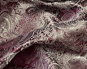 May include: Burgundy fabric with a silver paisley pattern. The fabric is woven with a raised texture.