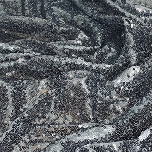 以下が含まれることがあります： 黒と銀のラメ生地で、質感のあるキラキラした表面です