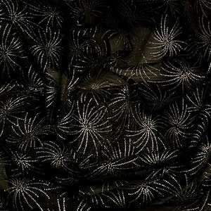 Könnte beinhalten: Schwarzer Stoff mit einem silbernen Glitzermuster aus stilisierten Feuerwerkskörpern.