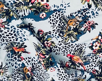 May include: A blue fabric with a tropical print featuring leopards, toucans, and flowers. The fabric has a white background with black leopard spots.
