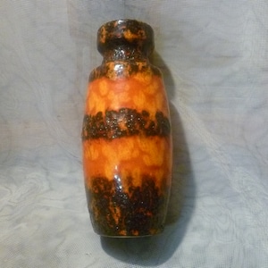 Peut inclure: Un vase en céramique de grande taille avec une surface texturée. Le vase présente des bandes horizontales orange et marron foncé. Le haut et le bas du vase sont marron foncé. C'est un objet décoratif.