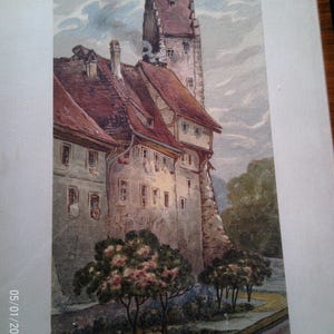 Könnte beinhalten: Aquarellmalerei eines europäischen Schlosses mit einem hohen Turm und roten Ziegeldächern. Das Kunstwerk zeigt detaillierte Architektur, Bäume mit rosa Blüten und einen bewölkten Himmel. Die Signatur des Künstlers und das Jahr 1913 sind sichtbar.