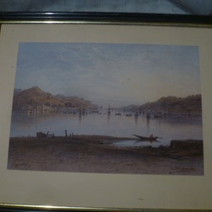 May include: A framed watercolor painting depicting a seascape with a small boat in the foreground and a town in the distance. The painting is set in a black frame with a gold trim.