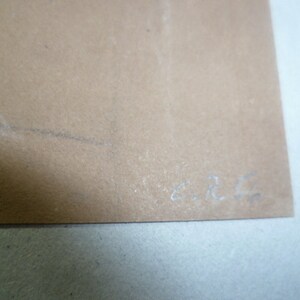 Puede incluir: Primer plano de una superficie de papel marr&oacute;n claro con la firma manuscrita "E.R.C."