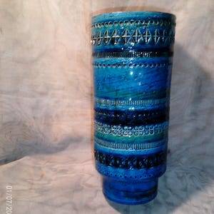 May include: A blue and green ceramic vase with a geometric pattern. The vase has a wide mouth and a narrow base.