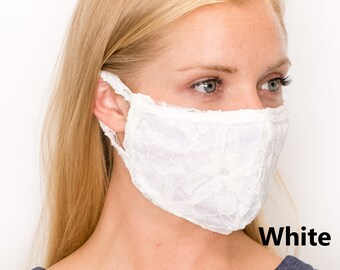 Puede incluir: Una mascarilla facial de encaje blanco con un patrón floral. La mascarilla la lleva puesta una persona con el pelo rubio. El texto "White" es visible en la esquina inferior derecha de la imagen.