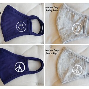 Puede incluir: Cuatro mascarillas reutilizables, dos azul marino y dos gris jaspeado. Las mascarillas presentan dos dise&ntilde;os diferentes: una cara sonriente blanca y un signo de paz blanco.