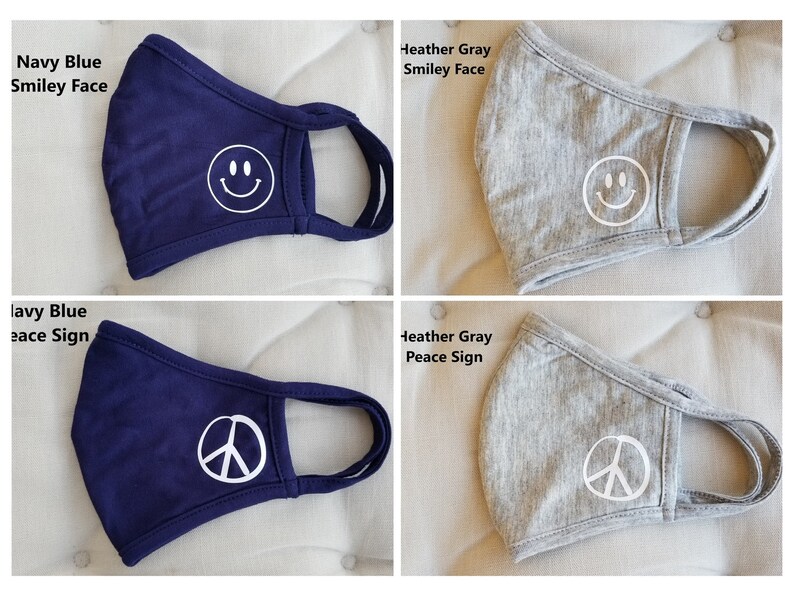 Puede incluir: Cuatro mascarillas reutilizables, dos azul marino y dos gris jaspeado. Las mascarillas presentan dos dise&ntilde;os diferentes: una cara sonriente blanca y un signo de paz blanco.