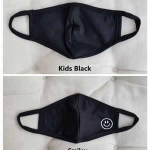 May include: Two black face masks for kids. The first mask is plain black. The second mask has a white smiley face on it. Both masks have elastic ear loops.