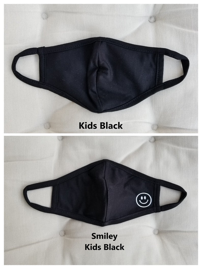 May include: Two black face masks for kids. The first mask is plain black. The second mask has a white smiley face on it. Both masks have elastic ear loops.