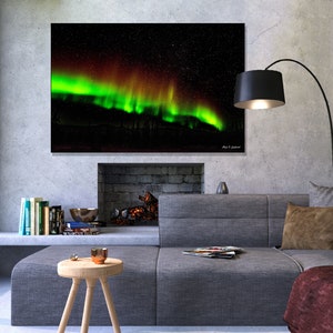 May include: A photograph of the aurora borealis, also known as the Northern Lights, in the night sky. The green and red lights dance across the sky, creating a beautiful and mesmerizing display.
