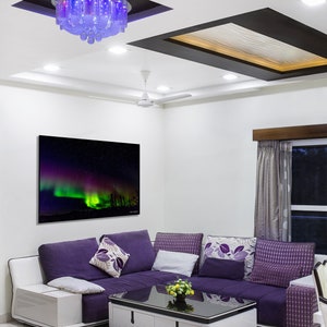May include: A modern living room with a purple sectional sofa, a coffee table, and a framed picture of the aurora borealis. The room has a white ceiling with a decorative light fixture and a ceiling fan.