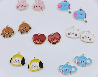 Puede incluir: Surtido de abalorios de esmalte de colores con personajes de dibujos animados. Los abalorios son de metal y tienen un acabado dorado brillante. Los personajes incluyen un conejito, un oso, un corazón, una nube, un koala y un perro.