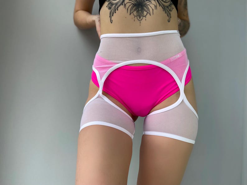 May include: A two-piece lingerie set featuring a bright pink bottom and a white and sheer top with white trim. The set is designed with a high waist and cut-out details, offering a modern and bold look.