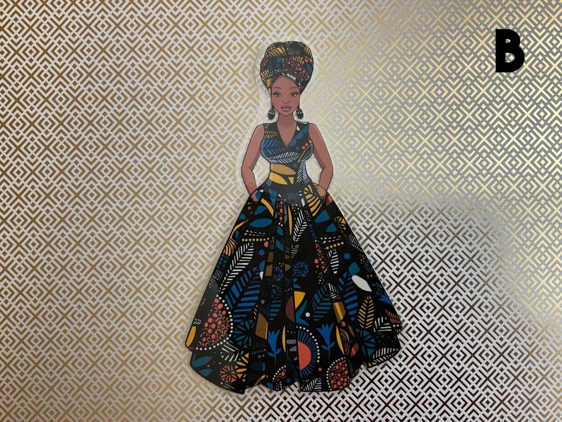 Op de afbeelding: Een zwarte en blauwe jurk met een kleurrijk bloemenpatroon. De jurk heeft een getailleerd bovenstuk en een volle rok. De vrouw draagt een hoofddoek en oorbellen.