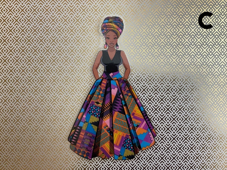 Op de afbeelding: Een vrouw draagt een kleurrijke, gepatroneerde rok en een zwart topje met een hoofddoek. De rok heeft een geometrisch patroon in tinten van paars, oranje, blauw en geel.