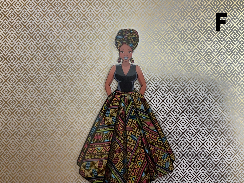 Op de afbeelding: Een vrouw in een zwarte jurk met een kleurrijke, gepatroneerde rok en een hoofddoek. De achtergrond is een goud-wit geometrisch patroon.
