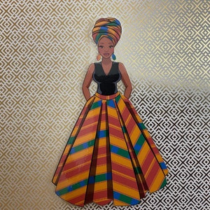 Op de afbeelding: Een vrouw die een zwarte, mouwloze jurk draagt met een kleurrijke, gepatroneerde rok en een hoofddoek. De achtergrond is een goud-wit geometrisch patroon.
