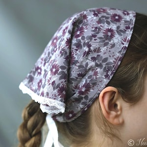 May include: A floral print head covering in shades of gray and purple, trimmed with white lace. The fabric features a pattern of flowers and leaves. The head covering is tied at the back with white ribbons.