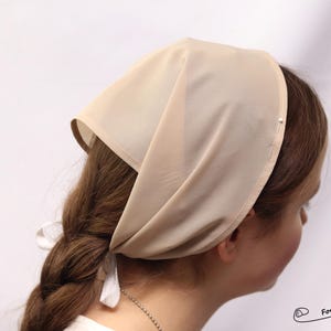 May include: A beige fabric head covering, also known as a prayer cap or prayer shawl, worn by some women as a religious head covering.
