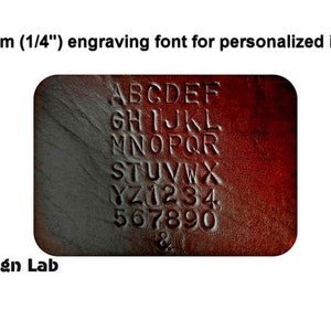 May include: A dark brown leather surface featuring a 6mm (1/4") engraved alphabet from A to Z, numbers 0 to 9, and an ampersand symbol. The text "6mm (1/4") engraving font for personalized items" appears above, with "Alex Design Lab" below.