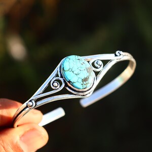 Peut inclure: Un bracelet en argent avec une pierre turquoise sertie dans un motif décoratif.