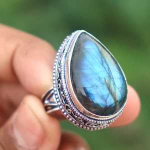 May include: A silver ring with a teardrop-shaped blue labradorite gemstone set in a detailed silver band.