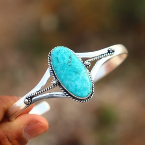 May include: A silver bracelet with a turquoise stone set in a silver bezel. The bracelet has a twisted wire design.