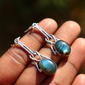 May include: A pair of silver dangle earrings with a blue labradorite gemstone in each. The earrings feature a Celtic knot design.