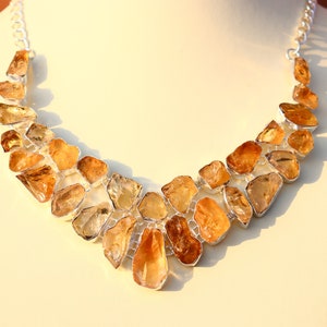 May include: A silver necklace with a cascading design of irregular, faceted, amber-colored stones.