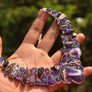 May include: A silver necklace with a variety of purple amethyst and iridescent abalone shell stones.