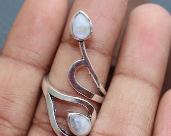 May include: A silver ring with a delicate, abstract design featuring two teardrop-shaped moonstone gems.