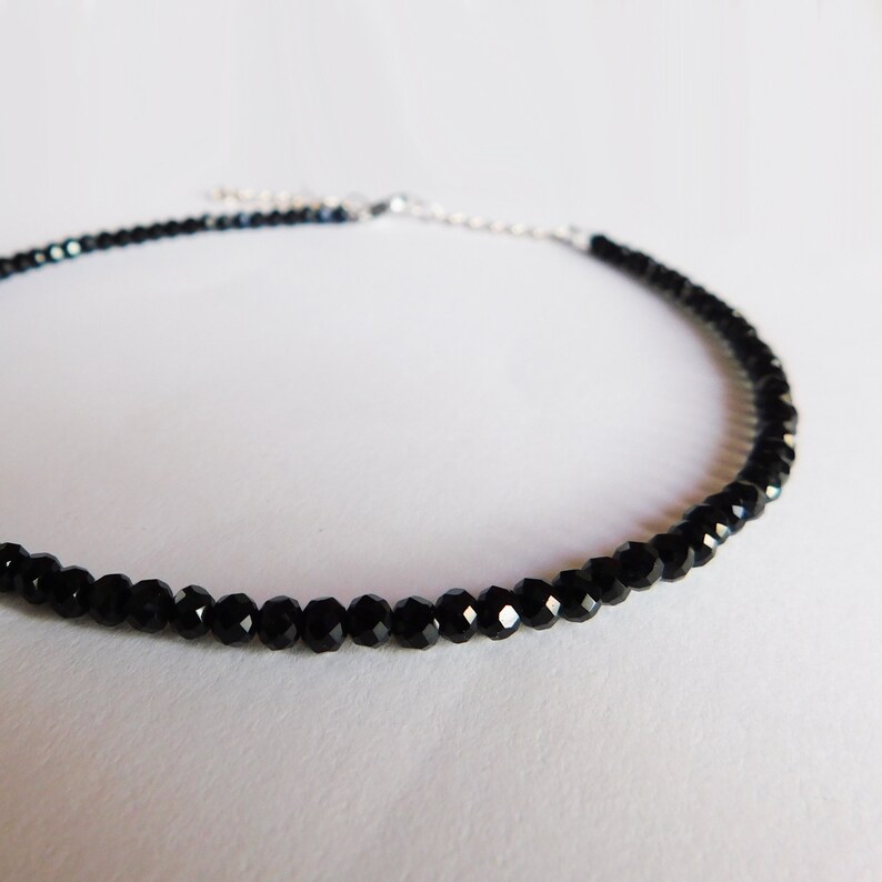May include: A delicate black choker necklace made with faceted black beads. The necklace is approximately 16 inches long and has a silver clasp.