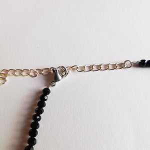 May include: A black beaded necklace with a silver clasp and a gold chain extender.
