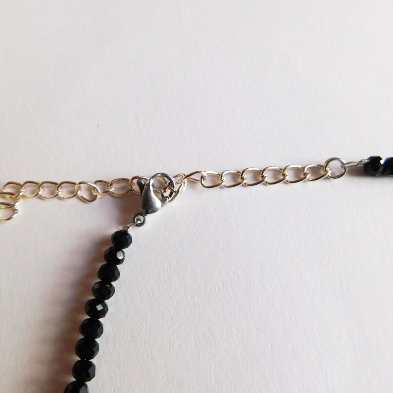 May include: A black beaded necklace with a silver clasp and a gold chain extender.