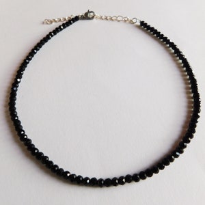 May include: A black choker necklace made of small, faceted beads. The necklace has a silver clasp.