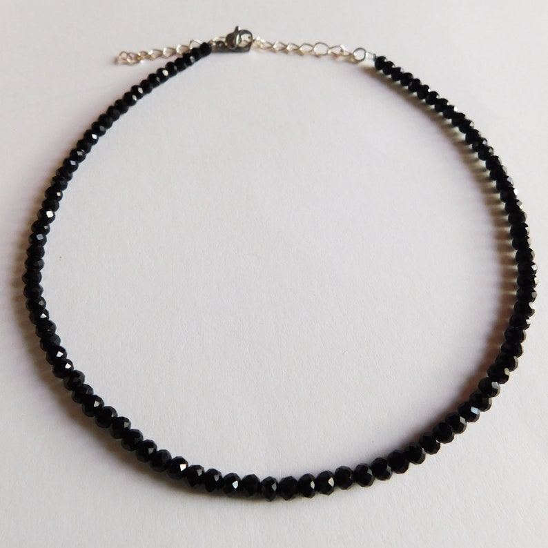 May include: A black choker necklace made of small, faceted beads. The necklace has a silver clasp.